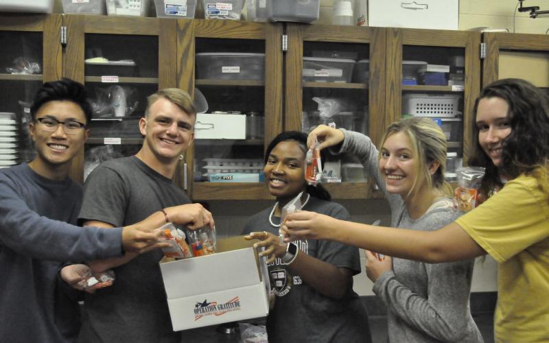 Arvin Dinh, Trevor Burton, Anike Tendell, Ashelyn Merce and J.J. Hayes are making a care package for troops.