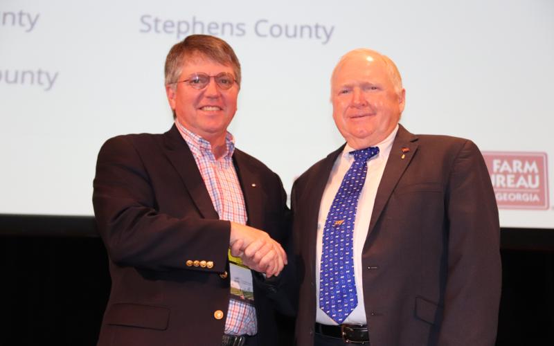 Georgia Farm Bureau president Gerald Long (right) congratulates Stephens County Farm Bureau president Mark Wilkinson on the county Farm Bureau’s being named a finalist for the McKemie Award.