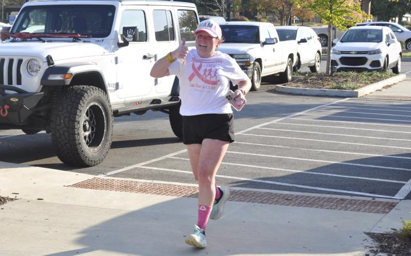 On Saturday morning, Oct. 18, the Tugalo Greenspace in downtown Toccoa was the site of a 5K race organized by Deidra Scott, of the CUREageoUS Crew, and Open Arms Clinic to raise awareness about breast cancer. Other local organizations, such as Currahee Movement Collective, participated in the event. Approaching the finish line here with a big smile and a thumbs up is Savannah Rothstein.