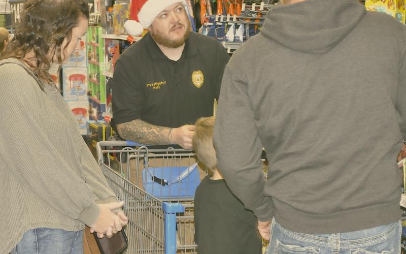 Toccoa police officer Timothy Kelly helps a family pick out items at the Shop with a Cop event at Wal-Mart in Toccoa on Saturday, Dec. 6.