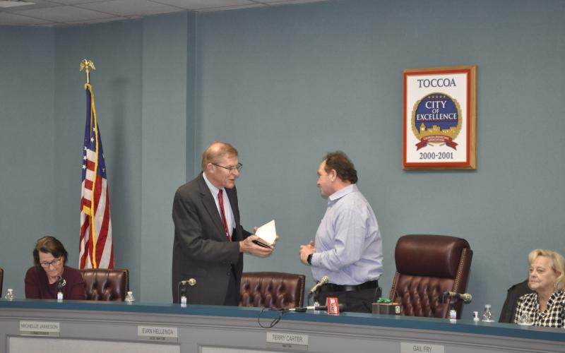 Toccoa mayor Evan Hellenga gives city commissioner Terry Carter a gift of appreciation for his service as mayor this year.