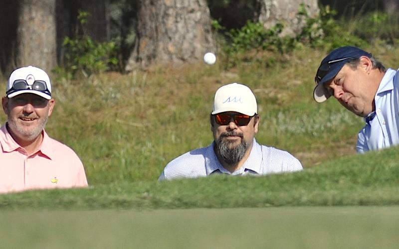 Teammates Benji Harrison and Josh Horton watch closely as Jamie Roberts chips to the ninth green.