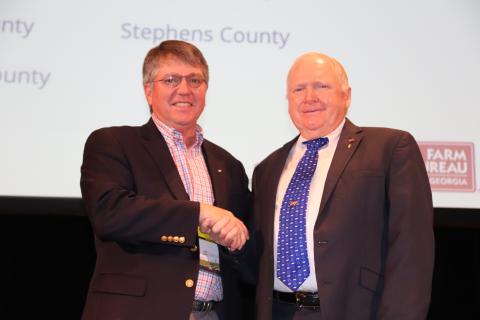 Georgia Farm Bureau president Gerald Long (right) congratulates Stephens County Farm Bureau president Mark Wilkinson on the county Farm Bureau’s being named a finalist for the McKemie Award.