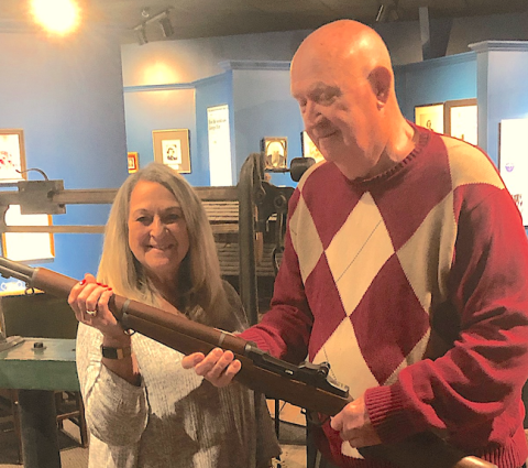 William Johnson (right) presents a World War II-era Garand M-1 rifle to Brenda Carlan of the Currahee Military Museum