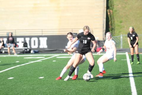 Blair Huddleton (18) dribbles the ball against two defenders.