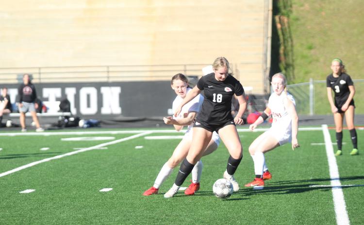 Blair Huddleton (18) dribbles the ball against two defenders.