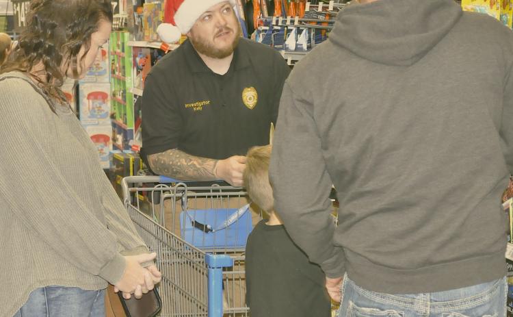 Toccoa police officer Timothy Kelly helps a family pick out items at the Shop with a Cop event at Wal-Mart in Toccoa on Saturday, Dec. 6.