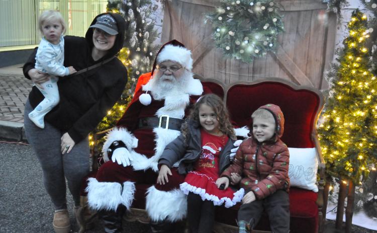Santa Claus came to downtown Toccoa on Friday night as part of the city’s annual ChristmasFest. He and Mrs. Claus set up a photo opportunity for parents and their children on Doyle Street during the festival. Getting their picture made with Santa Claus are Taylor Sidders, Sagi Sol, Xiius Sol, and Adaeus Sol.