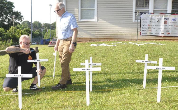 Tom Enlow, left, and Dave Cornelius, right, were busy Wednesday morning placing 36 white crosses on the lawn of the Toccoa American Legion Post 104 home at 610 E. Doyle Street in preparation for Memorial Day on Monday. The crosses represent every war in which the United States has waged since 1776 and the men and women who died in those conflicts. Enlow and Cornelius are both Marine Corps veterans and Post 104 members.