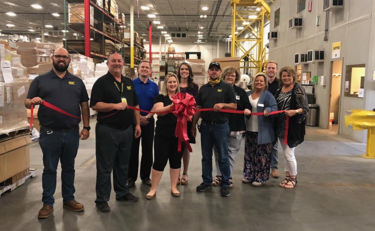 Pictured with Magnaflow staff and chamber of commerce members at last week’s ribbon-tying ceremony are Magnaflow director of distribution Bruce Mellhammer (second from left) and Magnaflow human resources business partner Hailey Beal (behind the ribbon).