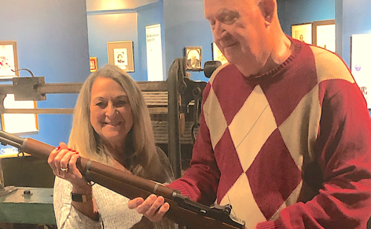 William Johnson (right) presents a World War II-era Garand M-1 rifle to Brenda Carlan of the Currahee Military Museum